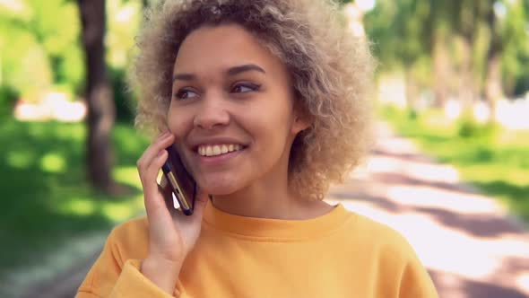 Cheerful Female with Cell Phone Walk on the Street alt