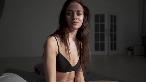 Cute Woman in Black Underwear Sit on the Big Bed and Stroking Her Long Amazing Hair alt
