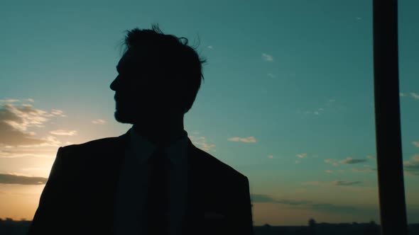 Businessman on the Background of the City at Sunset