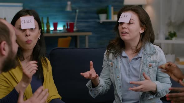 Multiethnic Friends Sitting on Couch Late at Night Playing Fuuny Guess Who Game alt