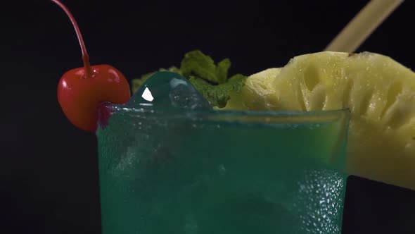 A Glass Green Cocktail Drink Rotating on Black Background. Close Up Shot. alt