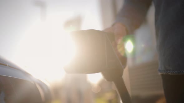 sun flared slow motion Plug electric car in at a EV charging station alt