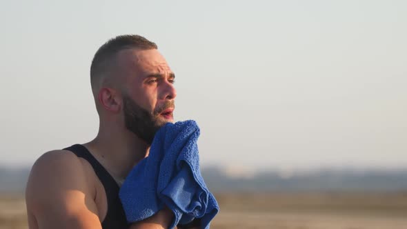 Man Tired and Sweat Wiping Face with Towel After Workout
