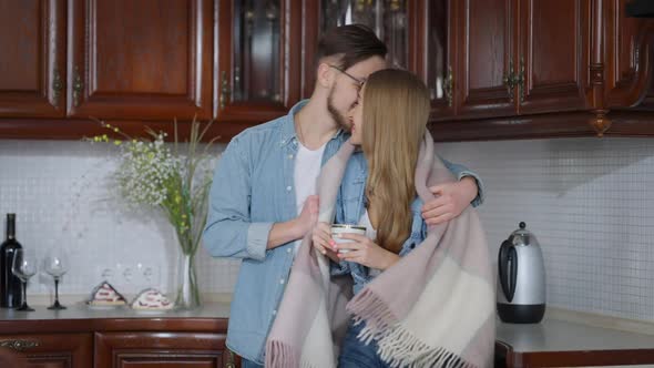 Young Smiling Handsome Man Entering Kitchen Wrapping Beautiful Woman in Blanket alt