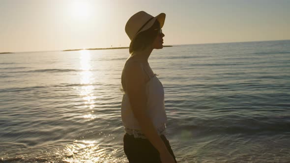 Steadycam shot of a Young attractive woman walking on the beach during sunset alt