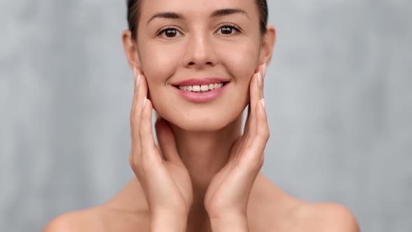 Happy Female Applying Moisturizing Cream on Face Touching Naked Body alt