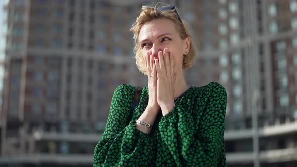 Portrait of Shy Caucasian Adult Woman in Green Dress Standing Outdoors in Sunlight Smiling Looking alt