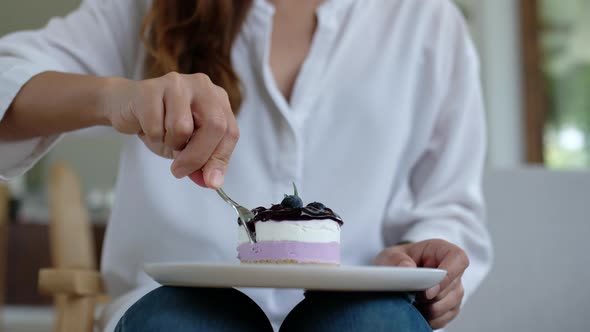 Closeup of a woman eating a piece of blueberry cheesecake