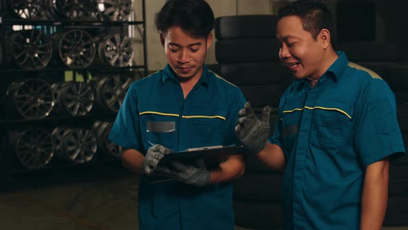 Two professional car mechanic using paperwork makes the oil and engine check to the car on lifted.