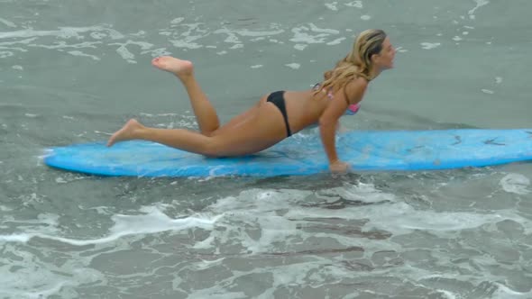 A young woman surfing in a bikini on a longboard surfboard. alt