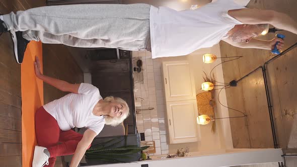 Mature Woman Sits on a Fitness Mat and Does Muscle Stretching Stretching on the Floor While Her alt