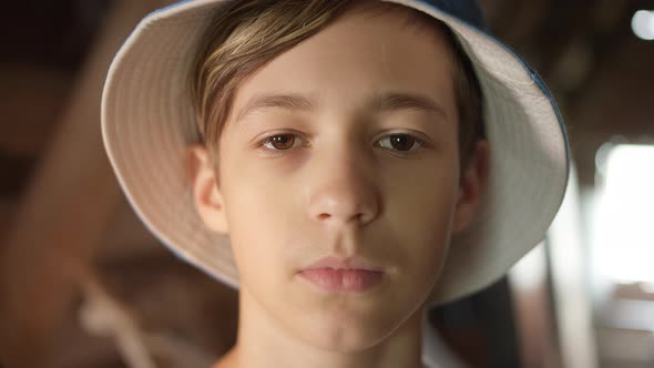 Portrait of a Sad Serious Boy in Hat Looking at the Camera Indoors Near the Window