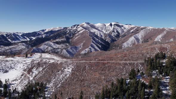 Drone shot pushing overtop of a mountain road with a mountain in distance alt