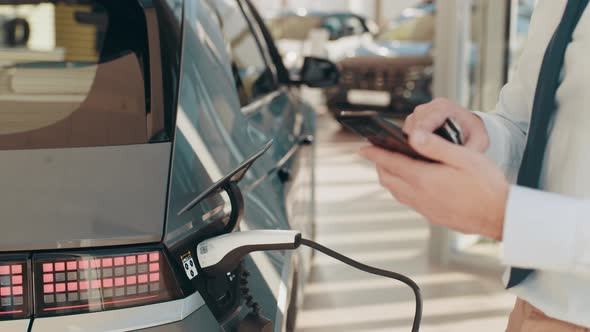 Unrecognizable Businessman Plugging Electric Car From Charging Station alt