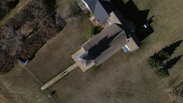 Top-down aerial view in 4k of a person walking along narrow paved path and going to church. 90 degre alt