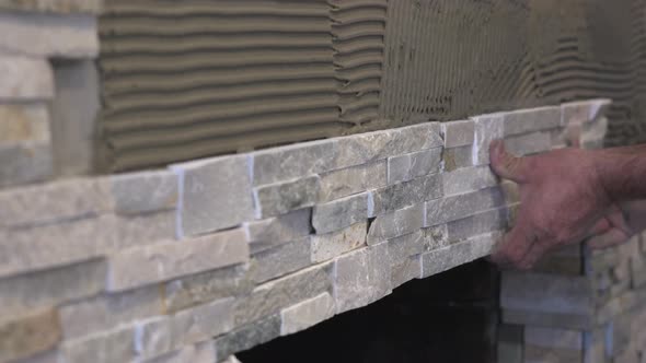 Male Worker Hands Setting Stacked Stone Tiles for a Fireplace alt