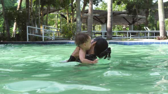 Lovely Mother with Baby in the Pool Swim Together