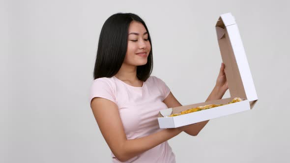 Asian Woman Opening Box And Showing Pizza Over White Background alt