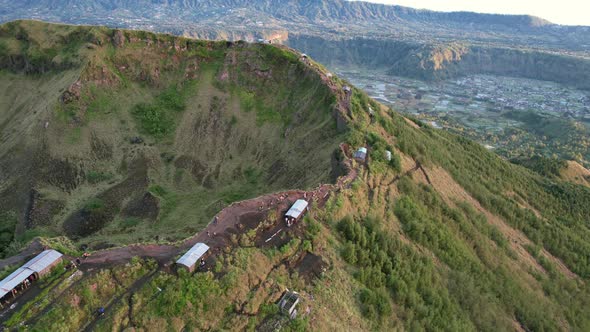 tourists walking the ridge along the crater rim of Mount Batur volcano during sunrise in Bali Indone alt