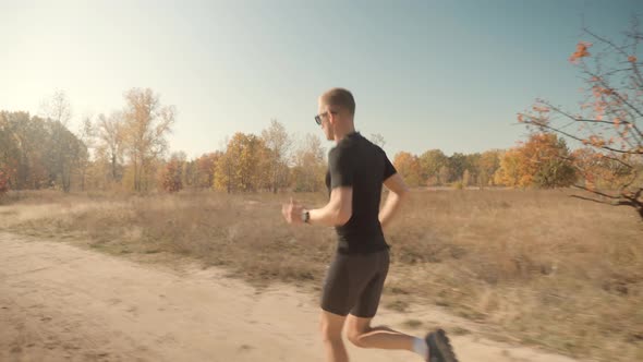 Running Man In Forest At Sunset. Runner Man Fit Athlete Legs Jogging On Trail Ready To Triathlon. alt