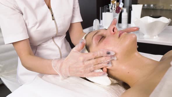 The Cosmetologist Applies a Moisturizing Cream to the Client's Face