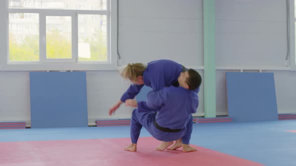 Male Ju-Jitsu Athlete Throwing Female Opponent during Fight alt