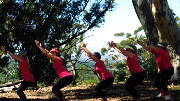 Female trainer assisting women while exercising in the boot camp alt