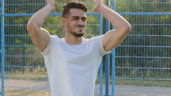 Young Arabic Middle Eastern Football Coach or Fan Emotionally Observes Process of Game Gives Advice alt