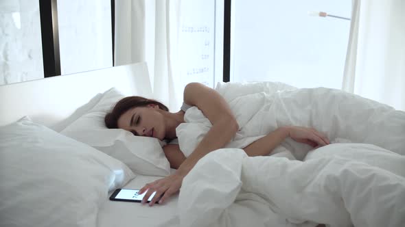 Alarm Clock On Phone. Woman Sleeping In Bed With White Linens alt