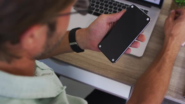 Caucasian male teacher having a videocall on smartphone in the classroom at school alt