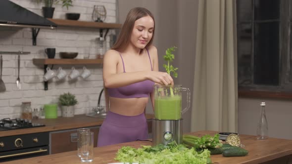Sporty Woman making, pouring, drinking green vegetable smoothie with blender.  alt