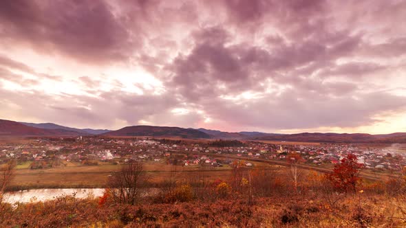 Aerial View of Village Houses in a Mountain Valley Against a Blue Sky with Occasional Clouds alt