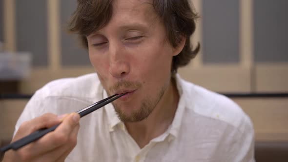 Slowmotion Shot of a Young Man Eatimg Asian Food in Japanese-korean Cafe alt