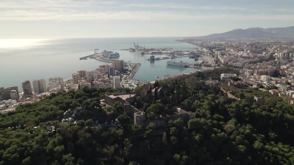 Gibralfaro castle on hill of Malaga city with sea in background. Aerial orbiting