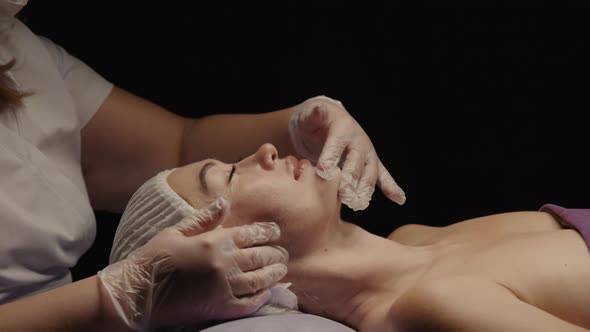 Woman Receiving Facial Massage in Spa Salon on Massage Table alt