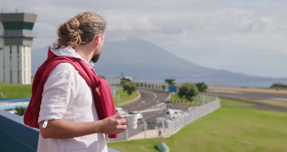 Man Sips His Drink While Observing an Airplane Landing alt