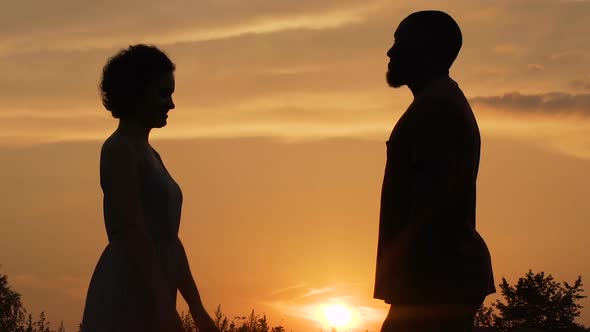 Silhouettes of Two Loving Hearts Stretching Their Hands to Meet Each Other alt