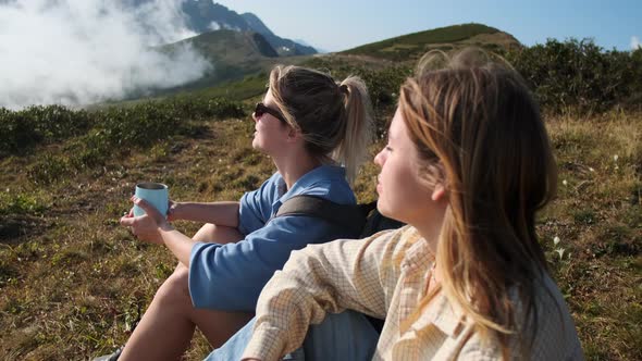 Halt on Top of Mountain During Hiking Two Young Women are Relaxing alt