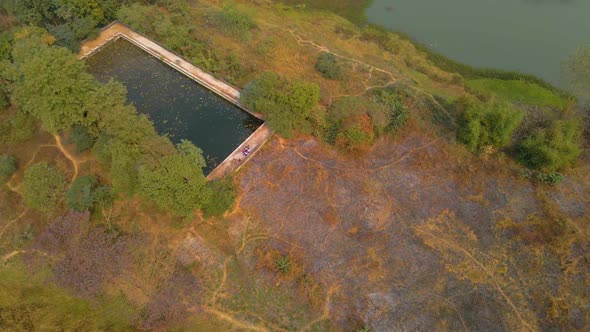 Aerial view of an old abandoned swimming pool surrounded by nature in India. alt