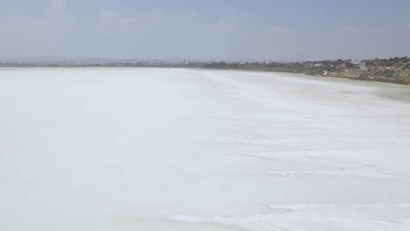 Aerial drone shot near the coast flying over a large salt lake in Cyprus alt