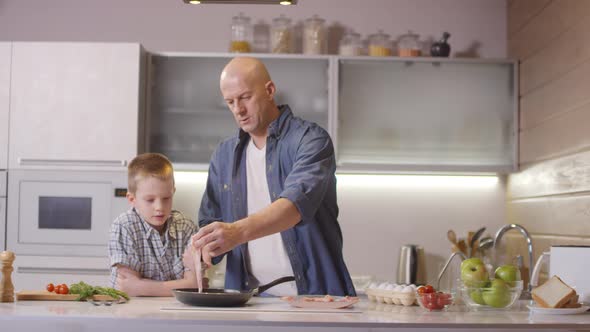 Father and Son Frying Bacon in Morning alt