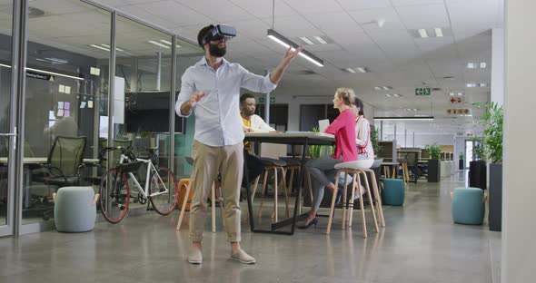 Happy biracial businessman using vr headset over colleagues in office alt