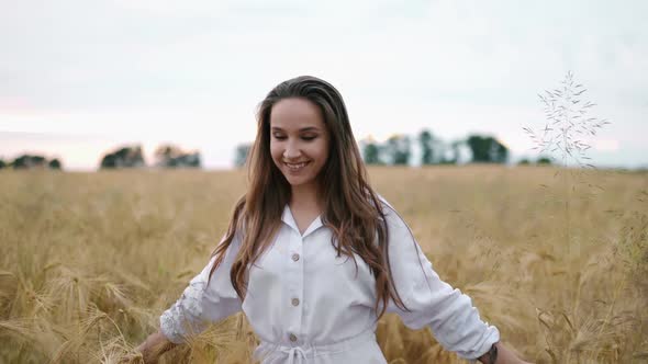 A Young Girl Happily Walking in Slow Motion Through a Field Touching with Hand Wheat Ears Beautiful alt