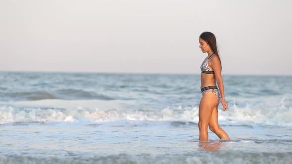 A Girl with Loose Hair Walks on the Sea with Waves and Enjoys the Sun alt