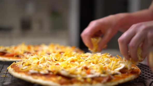 Chef at home putting mozzarella and cheddar cheese onto pizza close-up. Female cook applying fresh i alt