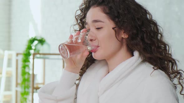 Woman Waking Up in Morning and Drinking a Glass of Water Girl Dressed in White Robe