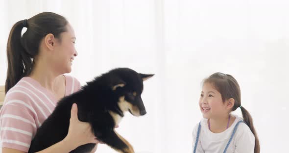 Mother and daughter playing with black dog on bed (4)