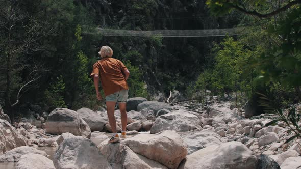 A Young Man Climbs Up the Rocks and Takes Pictures of the Surroundings ...