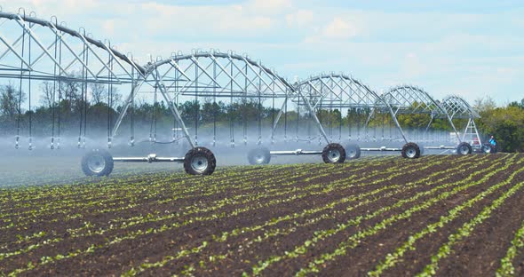 Massive Sprinkling Machine Is Moving Across the Field and Watering the Soil alt