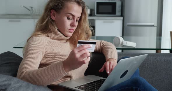Happy Young Woman with Curly Hair Holding Credit Card Using Laptop Payments at Home alt